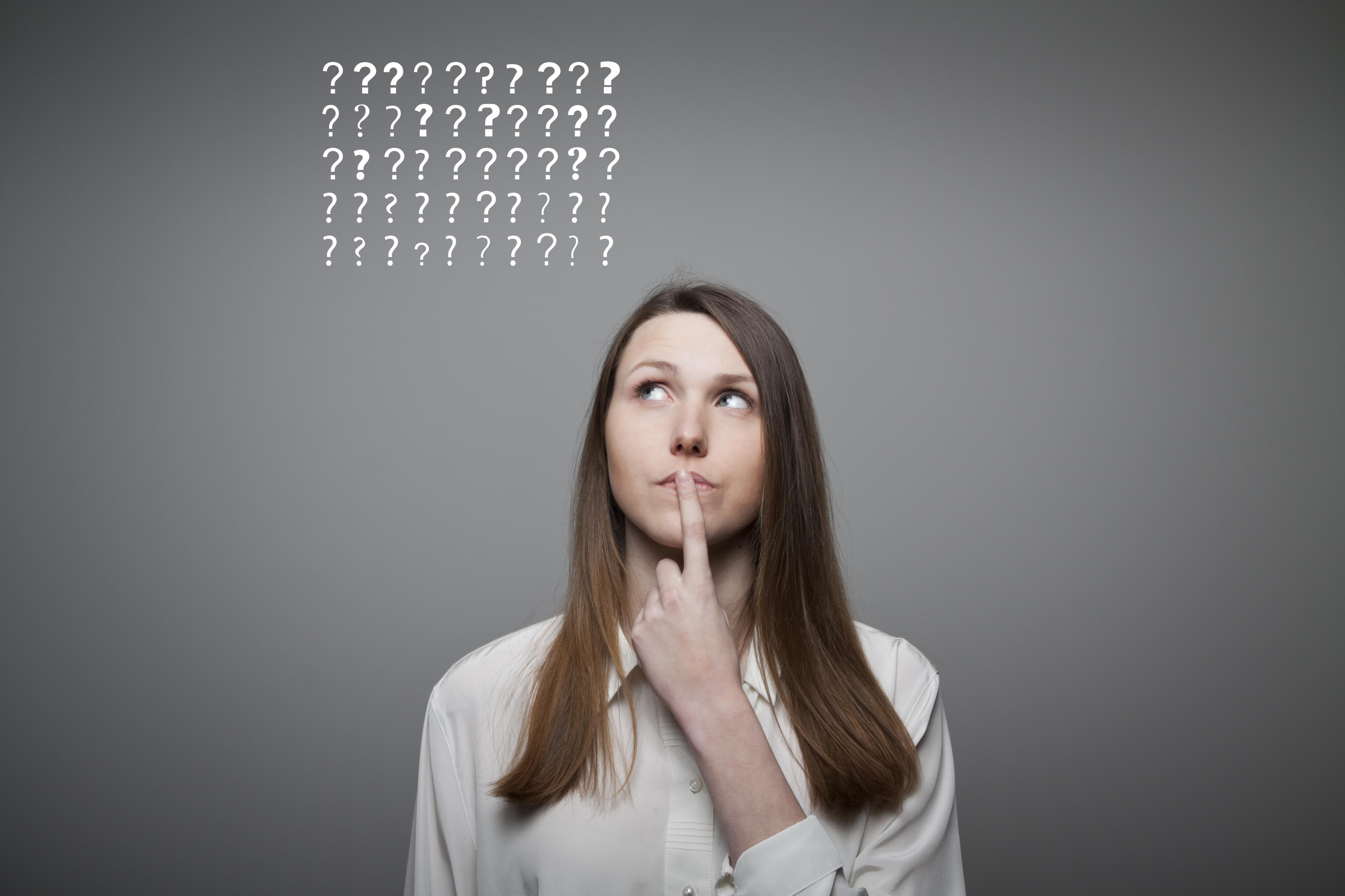 Young woman and many question marks above head