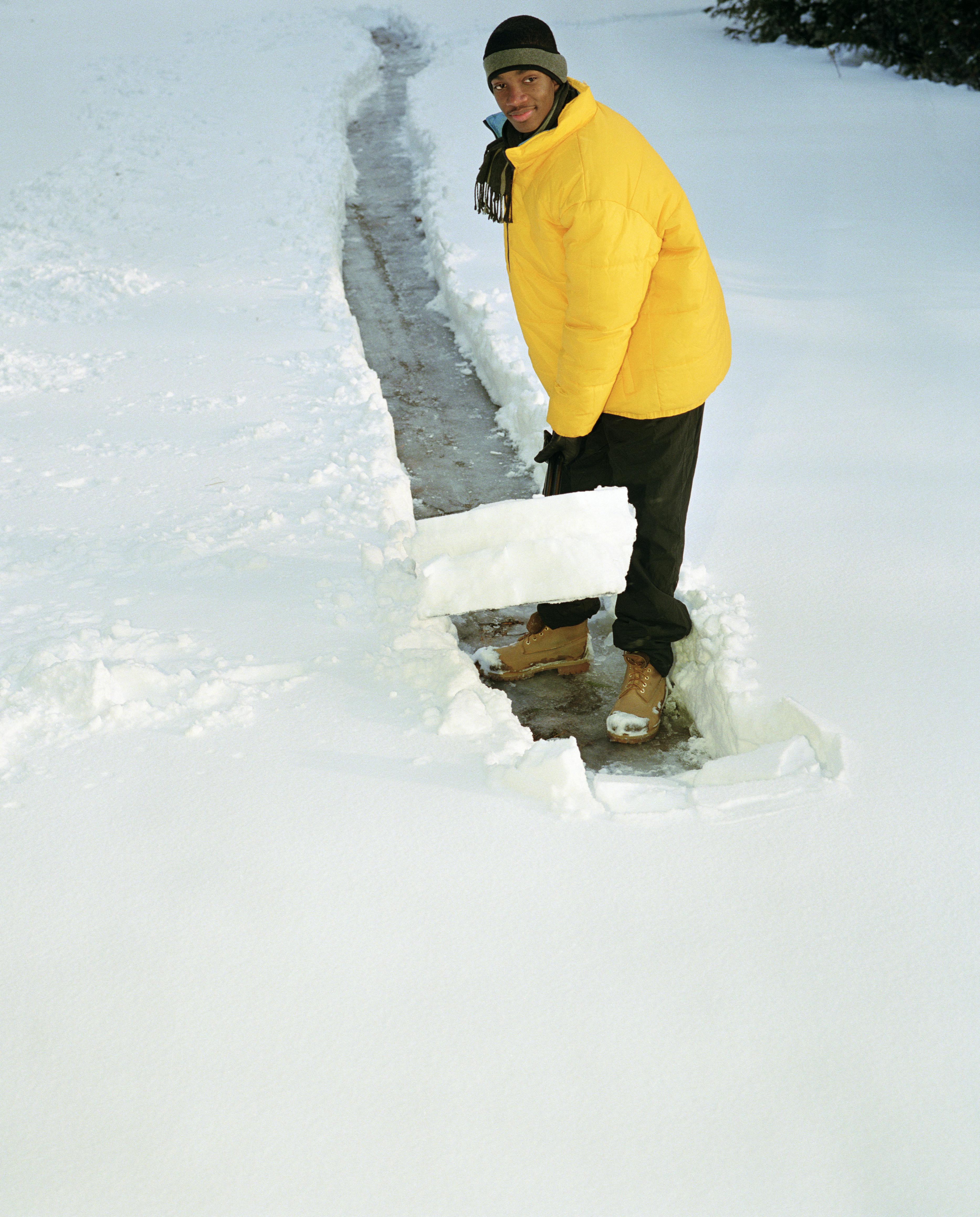 Teenage boy (16-18) shoveling path through snow, elevated view